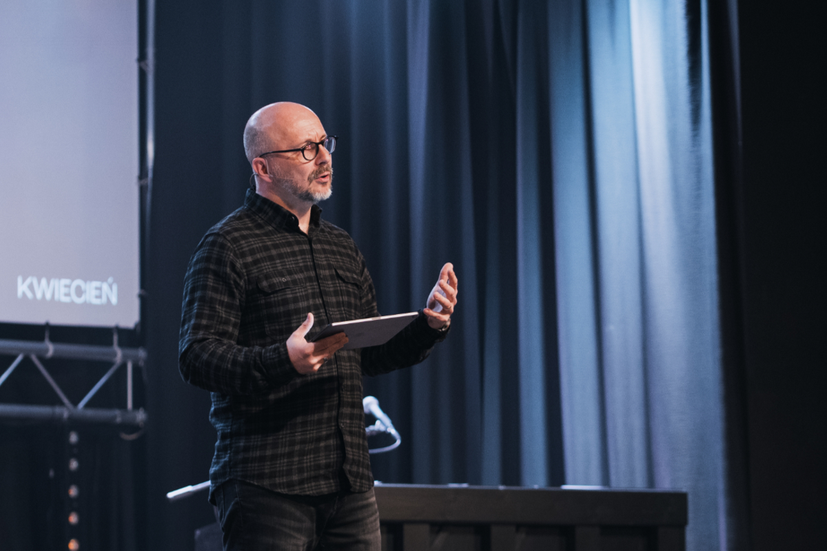A pastor holding a tablet preaches on stage