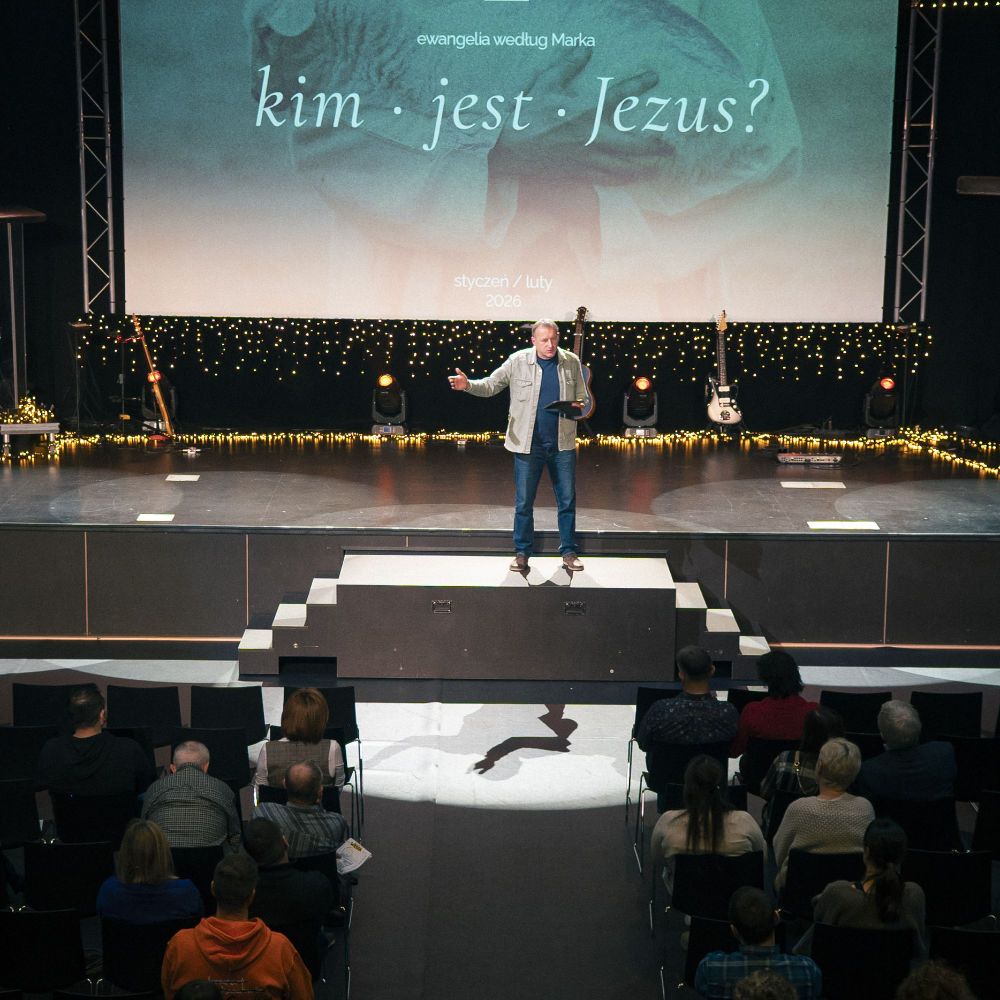 A preacher speaks from the stage, the screen reads “Kim jest Jezus?” (Who is Jesus?)