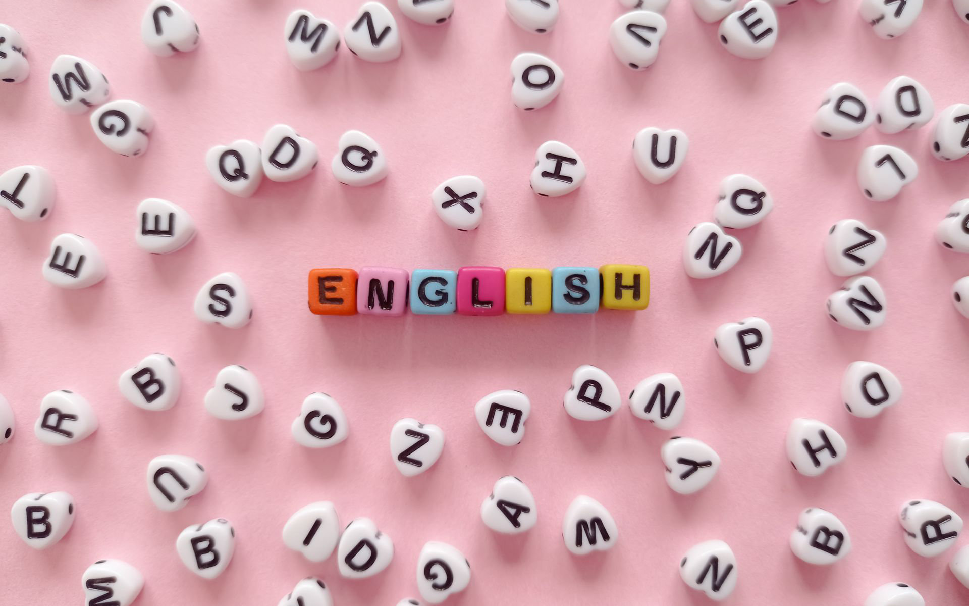 Кольорові намистини з літерами складають слово ENGLISH на рожевому тлі